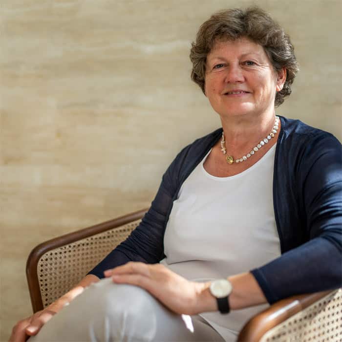 Renate Lorenz sitzt entspannt in einem Stuhl mit der Hand auf dem Knie.