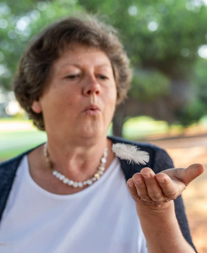 Renate Lorenz, die eine Feder über die erhobene Hand bläst