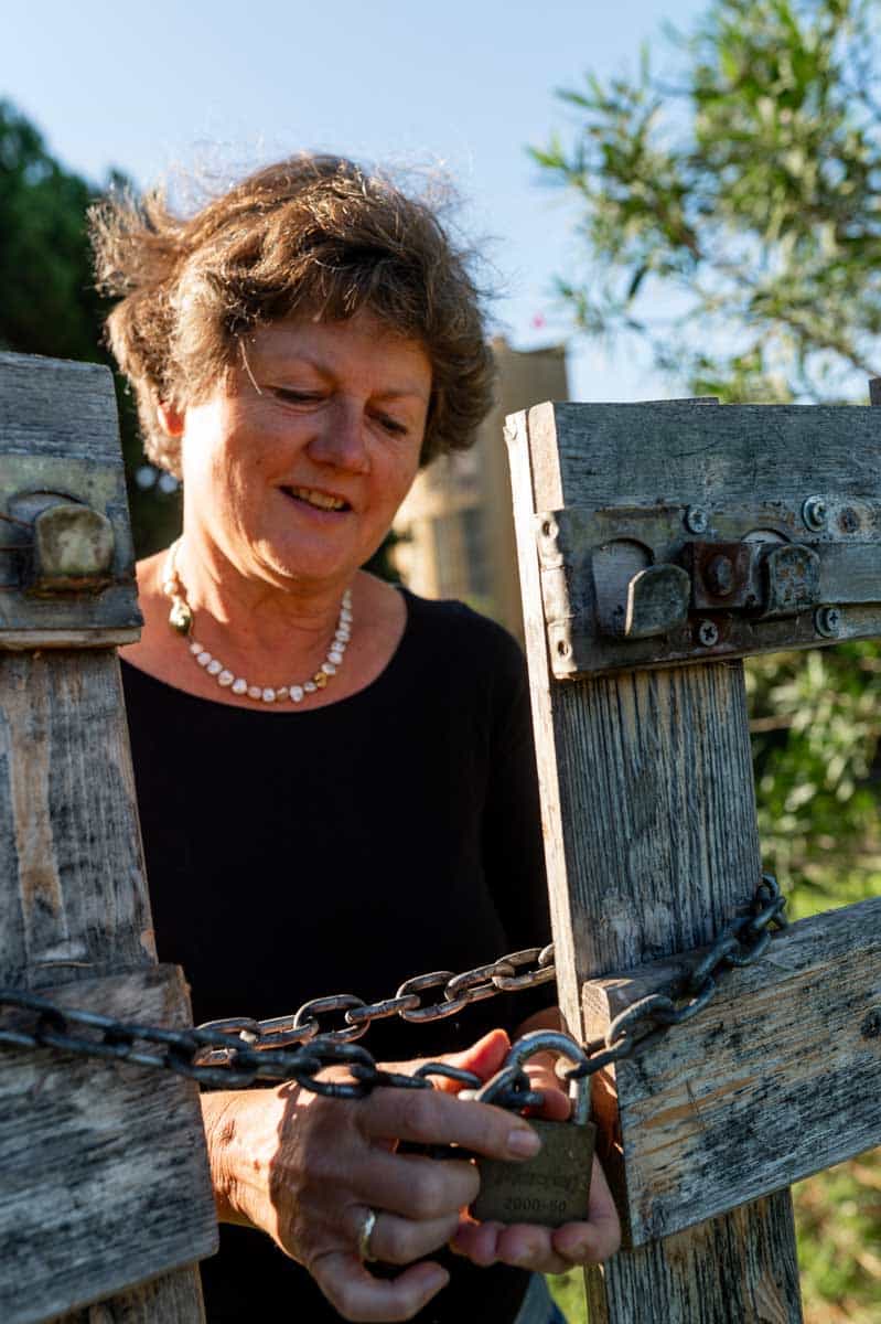 Renate Lorenz an einem Tor mit einer rostigen Kette und Schloss.